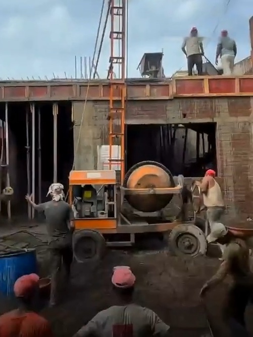 A crew casting a slab, with a concrete mixer and lift on site