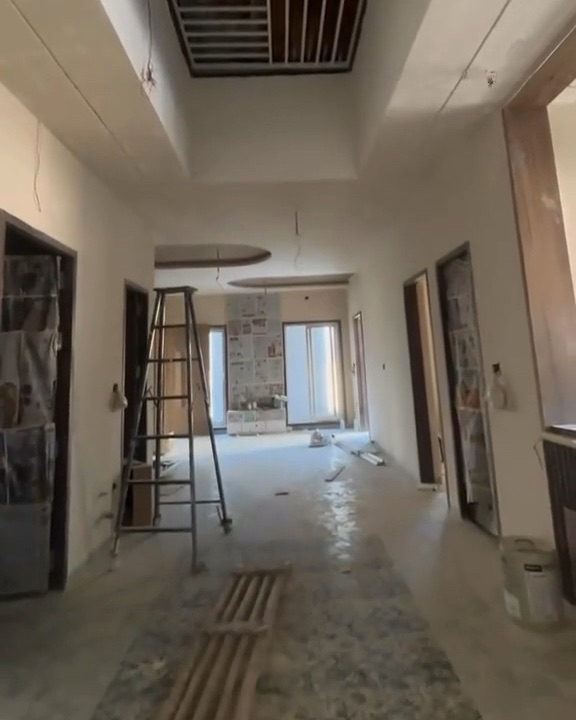 A corridor with new false-ceiling framing and a ladder, work in progress